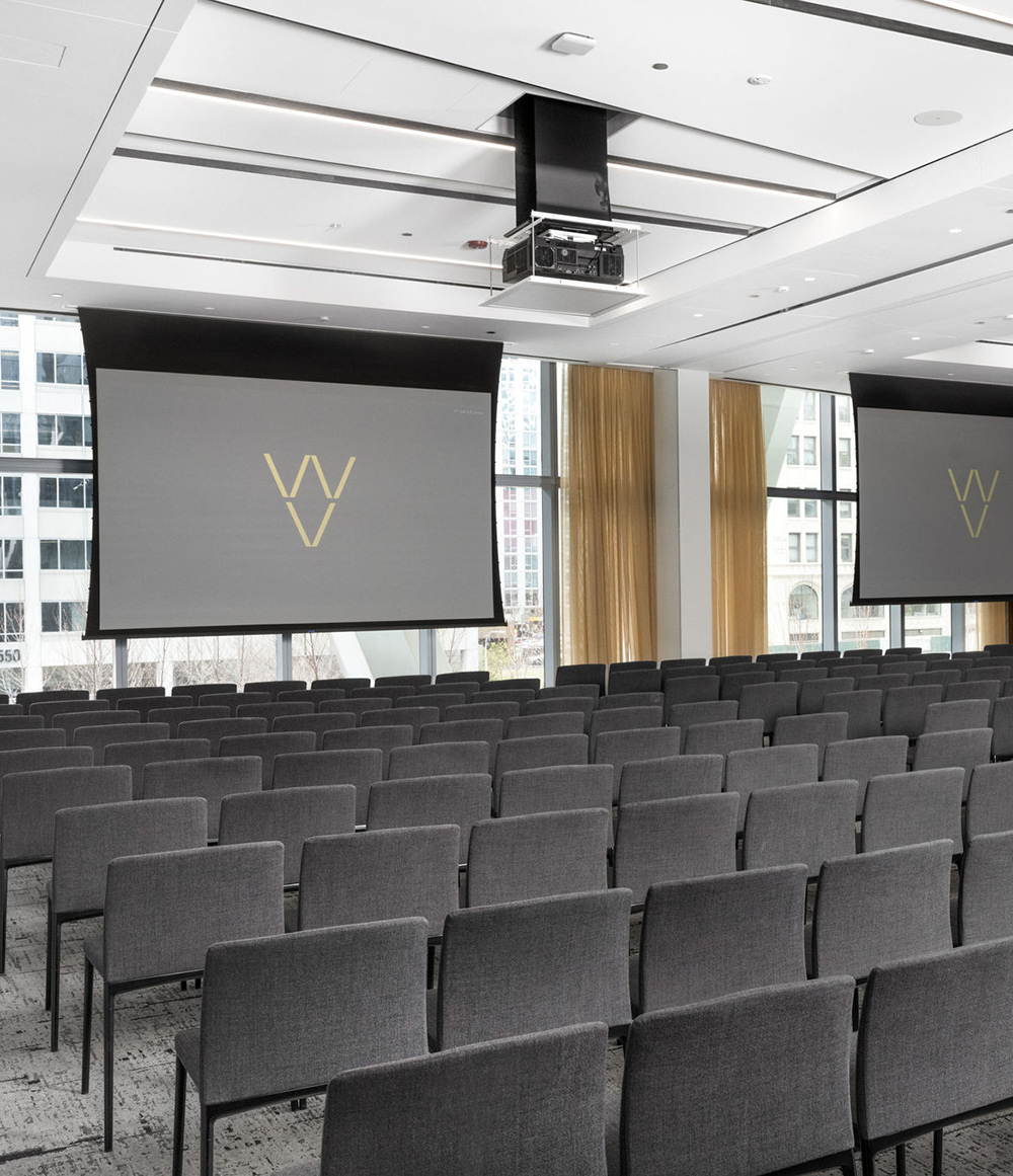 A large modern meeting room with ceiling projectors and screens