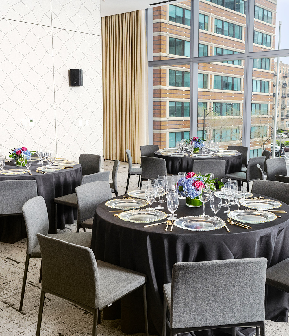 A event space with black linen dinning tables set with glassware